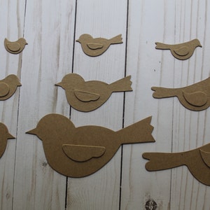 May include: A set of eight brown paper bird cutouts of varying sizes. The birds are all facing the right and have a simple design.