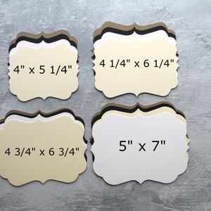 May include: Four different sizes of blank, cream-colored, scalloped-edge cardstock tags. The tags are stacked on top of each other. The measurements of each tag are printed on the front of the tag: 4" x 5 1/4", 4 1/4" x 6 1/4", 4 3/4" x 6 3/4", and 5" x 7".