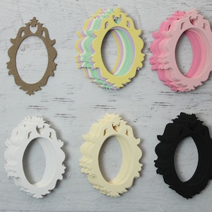 May include: A set of six oval-shaped paper frames with intricate designs. The frames are in various colors, including brown, yellow, pink, white, cream, and black.