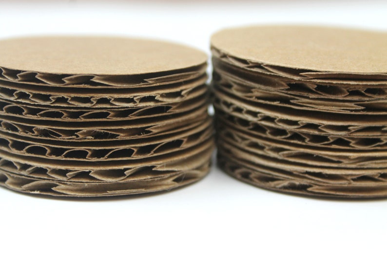 May include: Two stacks of brown cardboard circles, each circle is corrugated and has a slightly different size.