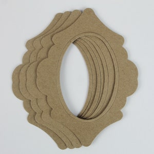 May include: A set of six brown cardboard oval frames with scalloped edges. The frames are stacked on top of each other.