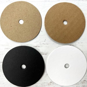 May include: Four round craft blanks with a hole in the center. Two are brown, one is black, and one is white.