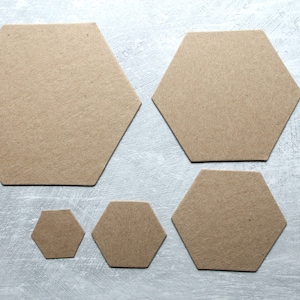 May include: Five brown cardboard hexagons of different sizes. The hexagons are arranged in a staggered pattern on a light gray background.