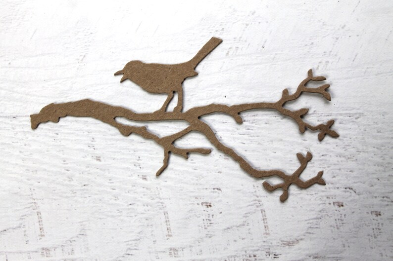 May include: A brown paper silhouette of a bird perched on a branch with leaves.