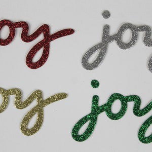 May include: Four glitter-covered "joy" cutouts in red, silver, gold, and green.