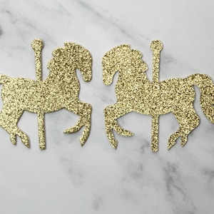 May include: Two gold glitter carousel horse cutouts. The horses are facing opposite directions and have a glitter finish.