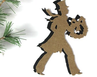 May include: A brown paper silhouette of a person in a top hat carrying a wreath with a bow. The silhouette is outlined in black.