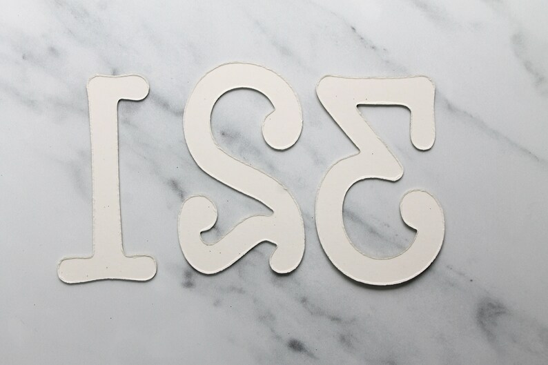May include: White paper cut-out numbers 1, 2, and 3 on a marble background.