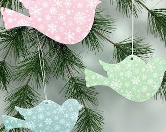 May include: Three wooden bird ornaments with snowflake patterns. The birds are pink, green, and blue.