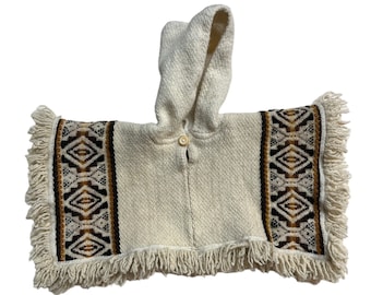 May include: A white hooded poncho with a geometric pattern in brown, black, and yellow along the edges. The poncho has a fringe border and a button closure.