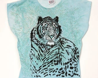 May include: A light blue t-shirt with a black and white tiger print. The shirt has a speckled pattern and the text "Adora" is printed on the tag.