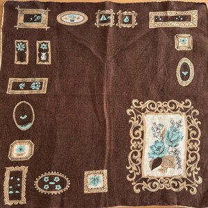 May include: A brown fabric handkerchief with a repeating pattern of blue and white floral designs in various frames. The frames are in shades of brown and gold.