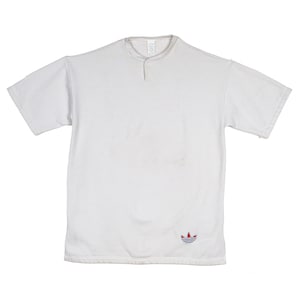 May include: White short-sleeved t-shirt with a button-up collar and a small Adidas logo on the bottom right.