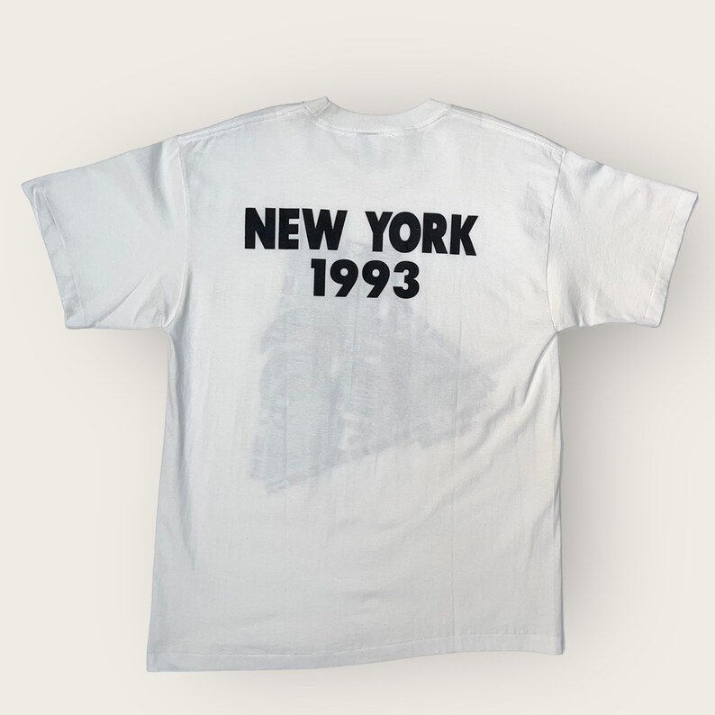 May include: White t-shirt with black text that reads "NEW YORK 1993".