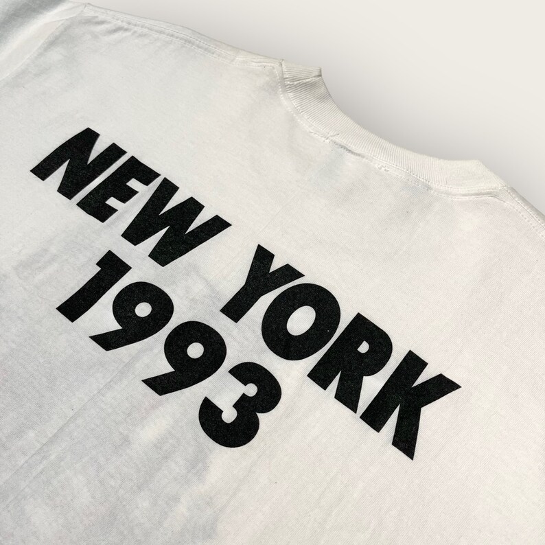 May include: White t-shirt with black text that reads "NEW YORK 1993".