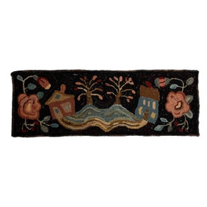 Pu&ograve; includere: Un tappeto fatto a mano con uno sfondo scuro che presenta una scena fantasiosa di due case, alberi e un fiume sinuoso. Le case sono rosa e blu, gli alberi sono marroni con foglie rosa e il fiume &egrave; blu e marrone. Il tappeto &egrave; bordato da una cornice marrone scuro.