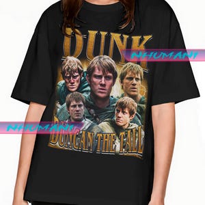 Könnte beinhalten: Schwarzes T-Shirt mit einem Vintage-Grafikdesign. Das Wort "DUNK" in goldfarbenen Buchstaben befindet sich über einer Collage von Gesichtern. Darunter steht der Text "DUNCAN THE TALL" in Gold.