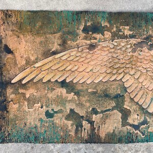 Puede incluir: Una pintura abstracta texturizada con un ala dorada grande en relieve sobre un fondo verde y marrón.
