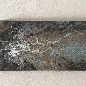 May include: Abstract painting with a black, white, brown, and blue colour scheme. The painting has a textured, splattered look with white lines running through it.