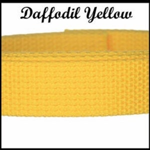 May include: A strip of daffodil yellow woven webbing strap with a textured surface. The text Daffodil Yellow is printed in a black cursive font above the yellow strap, which features a consistent grid-like pattern across its entire length.
