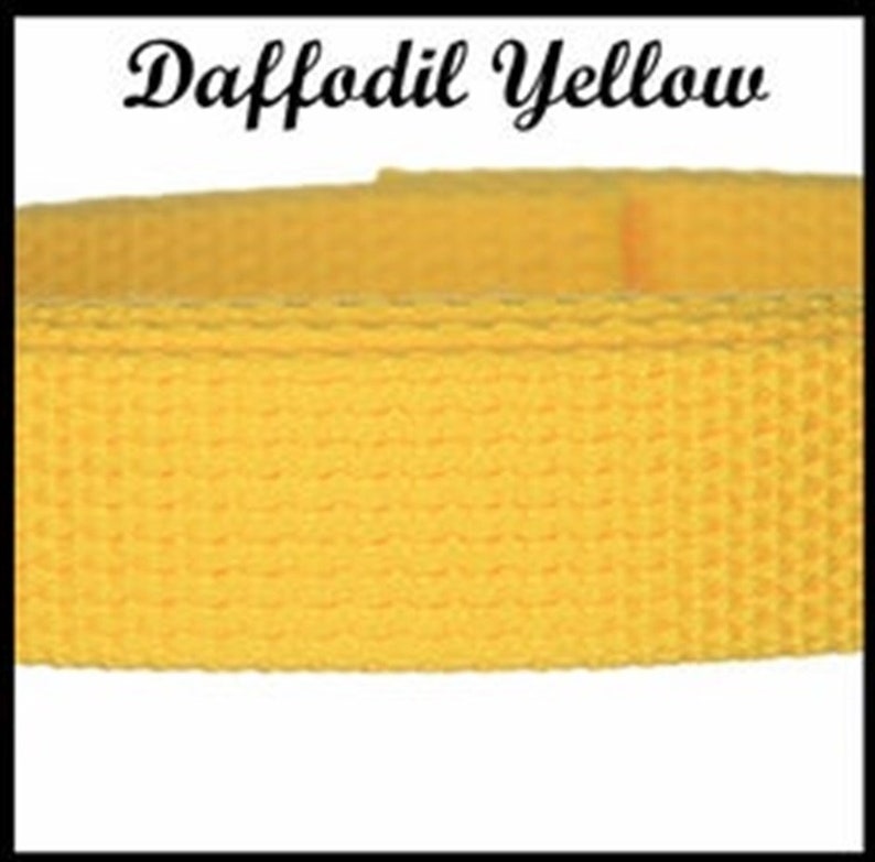 May include: A strip of daffodil yellow woven webbing strap with a textured surface. The text Daffodil Yellow is printed in a black cursive font above the yellow strap, which features a consistent grid-like pattern across its entire length.