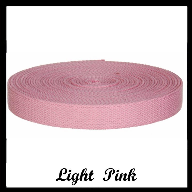 May include: A roll of light pink woven webbing tape featuring a consistent herringbone pattern throughout the material. The textile strip is coiled into a flat, circular shape with a smooth, uniform texture and edges, labeled with the text Light Pink.