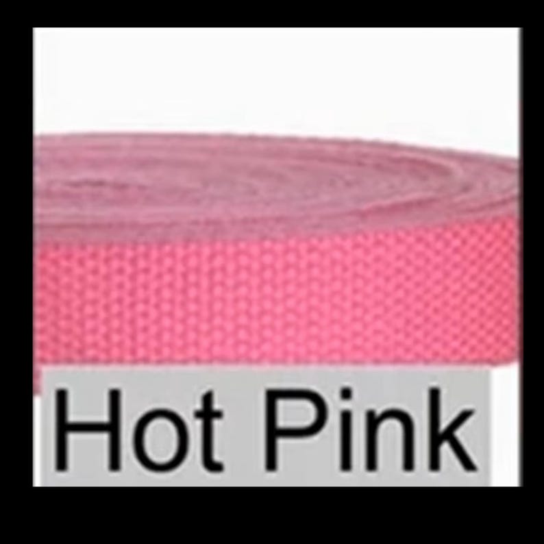 May include: A roll of hot pink woven webbing strap featuring a tight, durable texture. The material is coiled into a circular shape, displaying a consistent vibrant color throughout. A light gray rectangular label with the text Hot Pink is visible.