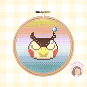 Puede incluir: Un aro de bordado de punto de cruz con un fondo de arcoíris colorido y un búho de dibujos animados con los ojos cerrados. El búho es marrón, amarillo y rojo. El aro es de madera y tiene un tornillo de metal.