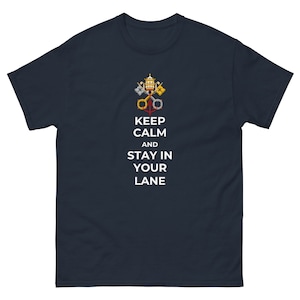 May include: Navy blue t-shirt featuring the text "KEEP CALM AND STAY IN YOUR LANE" in white, with a gold, silver, and yellow emblem above the text. The t-shirt is made of a soft material.