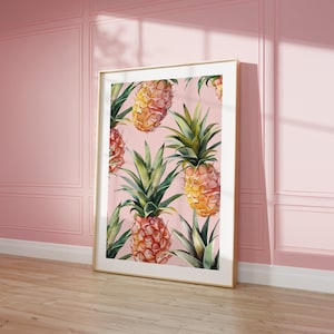 Könnte beinhalten: Ein gerahmter Druck mit rosa Hintergrund und einem Muster aus Aquarell-Ananas. Die Ananas sind gelb und orange mit grünen Blättern.