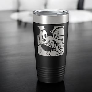 May include: Black stainless steel tumbler with a white and black image of Mickey Mouse and Pluto. The tumbler has a black lid and a textured exterior.
