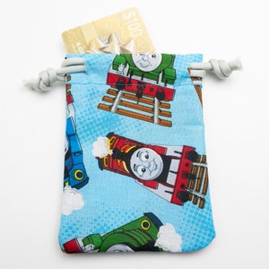 May include: A blue drawstring bag with a Thomas the Tank Engine print. The bag is filled with a gift card with a $100 value.
