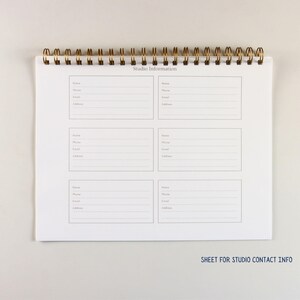 May include: A white spiral-bound notebook with gold-colored metal rings. The notebook pages are printed with lined sections for contact information, including name, phone, email, and address. The text "Studio Informations" is printed at the top.