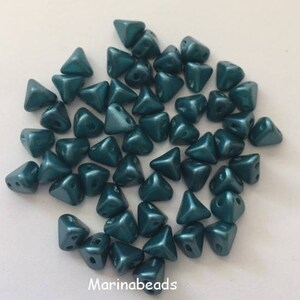 May include: A pile of teal green triangle-shaped beads with a metallic finish. The beads are small and have two holes.