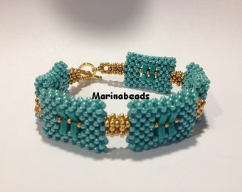 May include: Teal and gold beaded bracelet with a square design. The bracelet is made with small beads and has a gold clasp.