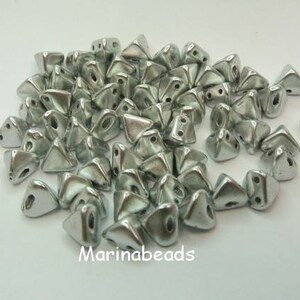 May include: A pile of silver-colored triangular beads. The beads are small and have a shiny finish.