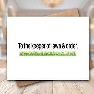 May include: A white greeting card with the text "To the keeper of lawn & order." The text is in black, above a strip of green grass. The card is on a brown envelope, set on a light wood surface.