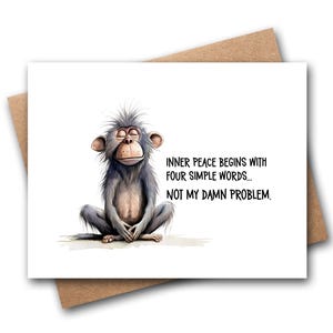 May include: A white greeting card featuring a cartoon illustration of a grey monkey sitting in a meditative pose with eyes closed. The text on the card reads: INNER PEACE BEGINS WITH FOUR SIMPLE WORDS... NOT MY DAMN PROBLEM. The card is placed on a brown envelope.