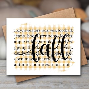 May include: A white greeting card with a yellow and white gingham background pattern. The card features black text listing fall-themed words including cozy, sweaters, scarves, football, jeans, boots, crunchy leaves, apple cider, pumpkin patches, giving thanks, harvest, candy corn, caramel apple, pie, corn mazes, hayrides, acorns, autumn, bonfires, chestnuts, and the word fall in large script.