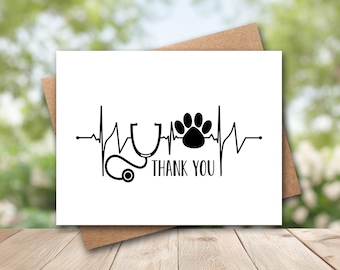 May include: A white rectangular greeting card featuring a black graphic design of a heartbeat line, a stethoscope, and a paw print. The text THANK YOU is printed in black capital letters below the stethoscope and paw print graphic elements.