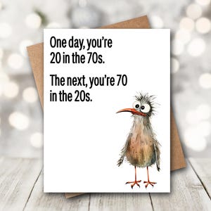 May include: A white ceramic mug with a black handle and the text "But First, Coffee" in a bold, black font. The mug is filled with a dark liquid, likely coffee, and sits on a light-colored surface.