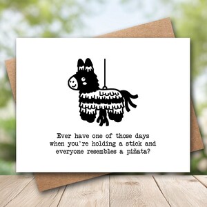 May include: A white greeting card featuring a black graphic illustration of a donkey piñata. Below the illustration, the text reads: Ever have one of those days when you're holding a stick and everyone resembles a piñata? The card is paired with a brown envelope.