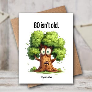 May include: Greeting card with a cartoon tree illustration. The tree has a surprised expression and green leaves. Text on the card reads "80 isn't old. If you're a tree."
