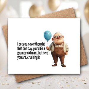 May include: A white greeting card featuring a cartoon illustration of an elderly person with glasses wearing brown overalls and holding a blue balloon. The text reads: I bet you never thought that one day, you’d be a grumpy old man...but here you are, crushing it.