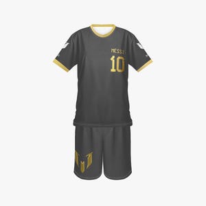 Może przedstawiać: Ciemnoszary strój piłkarski ze złotymi akcentami. Koszulka ma napis "MESSI" i numer "10" w kolorze złotym. Spodenki mają złote logo. Strój ma złote wykończenia na rękawach i kołnierzu.
