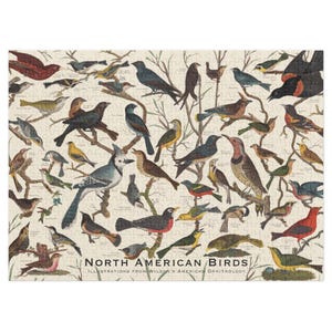 May include: A jigsaw puzzle featuring illustrations of North American birds. The puzzle shows various bird species perched on tree branches, with a cream-colored background. The text "North American Birds" is printed at the bottom.