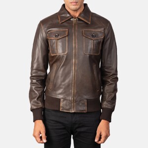 Könnte beinhalten: Eine braune Lederjacke mit Reißverschluss und zwei großen Pattentaschen. Die Jacke hat einen Used-Look und einen gerippten Strickkragen, -bündchen und -bund.