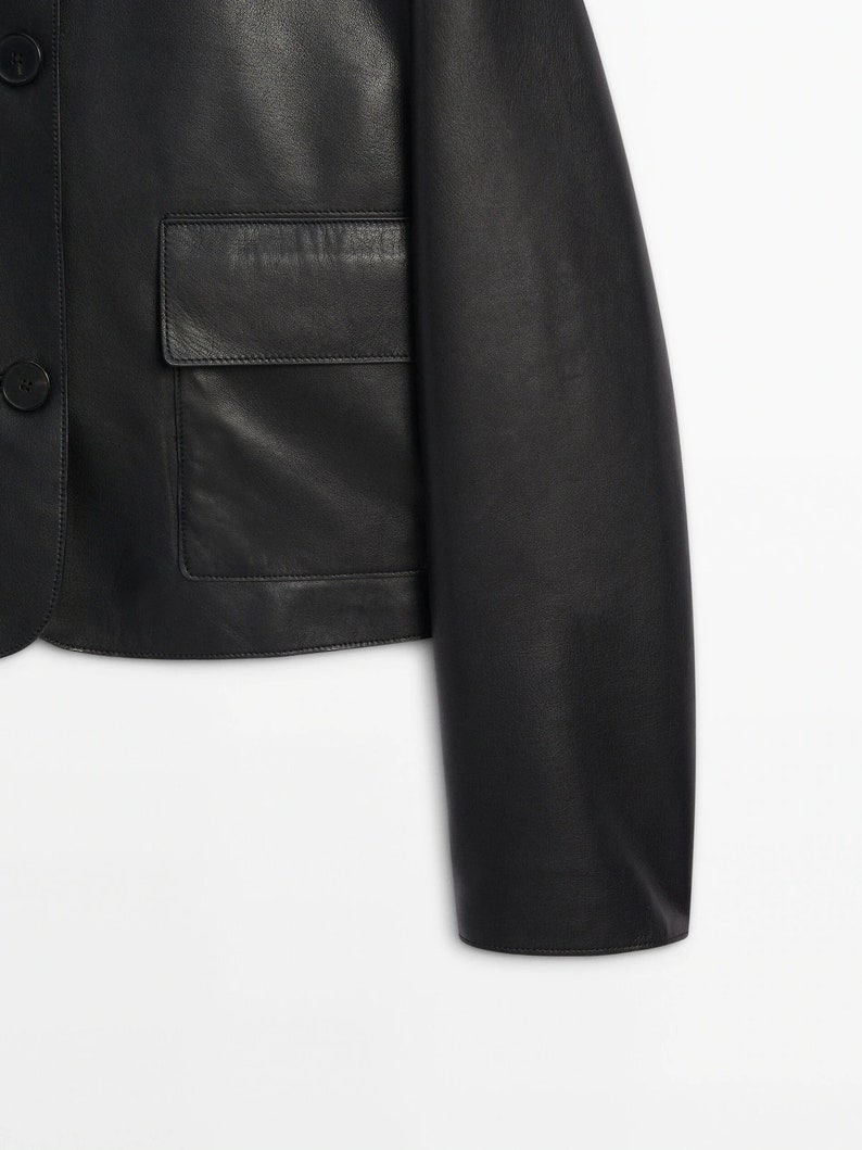 May include: A black leather jacket with a button closure and a patch pocket on the front.