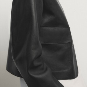 May include: A black leather jacket with a cropped silhouette and a large patch pocket on the front.