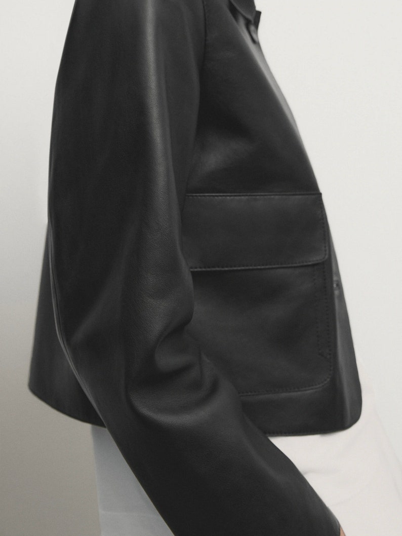 May include: A black leather jacket with a cropped silhouette and a large patch pocket on the front.
